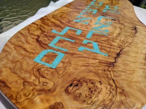 The reverse side showing the gorgeous grain and live edge. Closeup detail of the wood and turqoise.